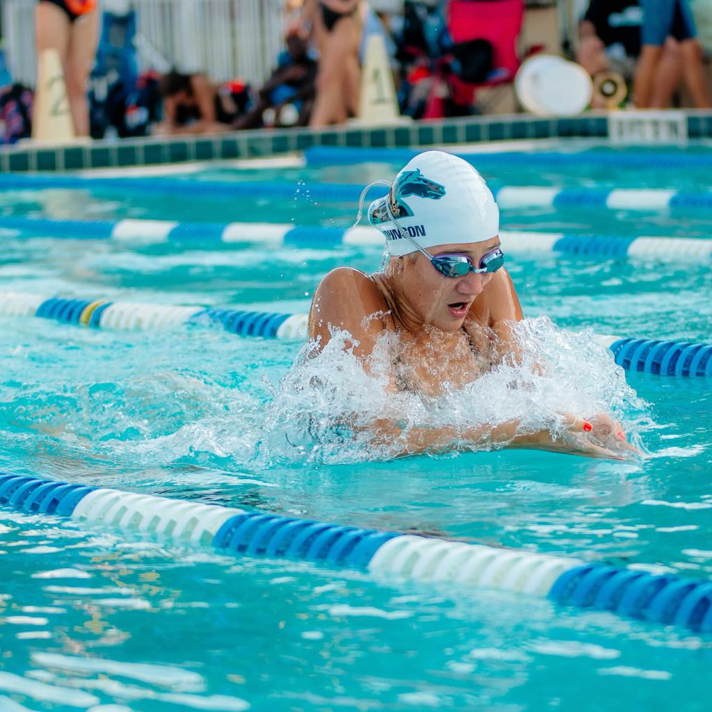 An individual swimming in a pool, aiming to qualify for a state competition.