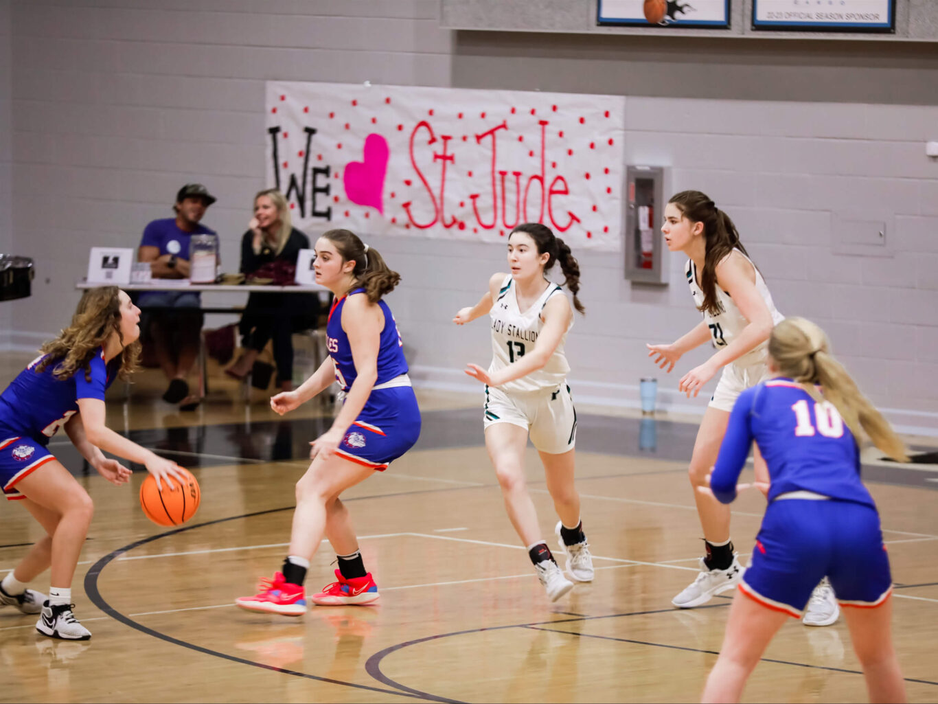 A group of girls engaged in a spirited game of basketball in a gym.