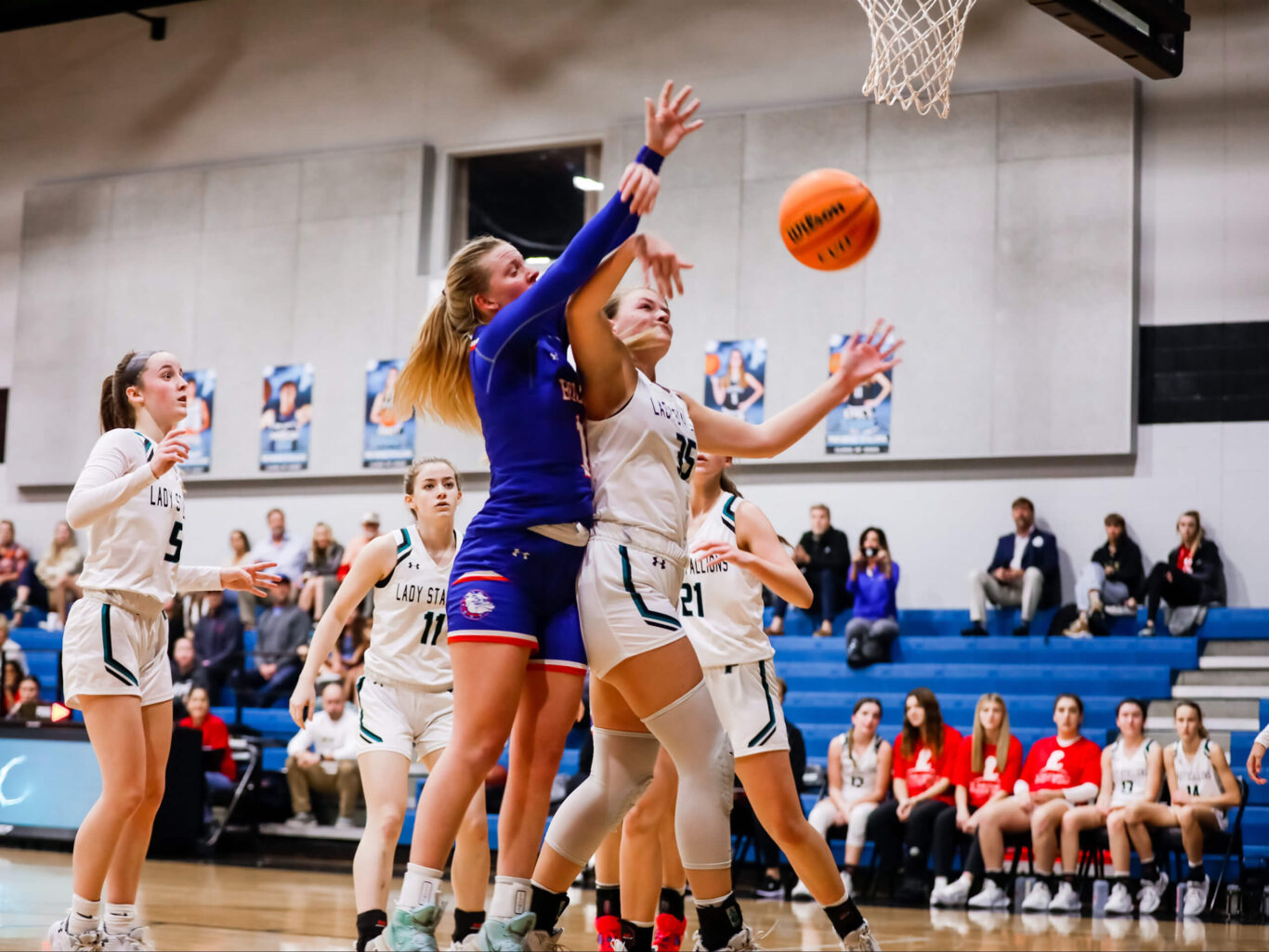 A girl is playing basketball and attempting to block a shot.
