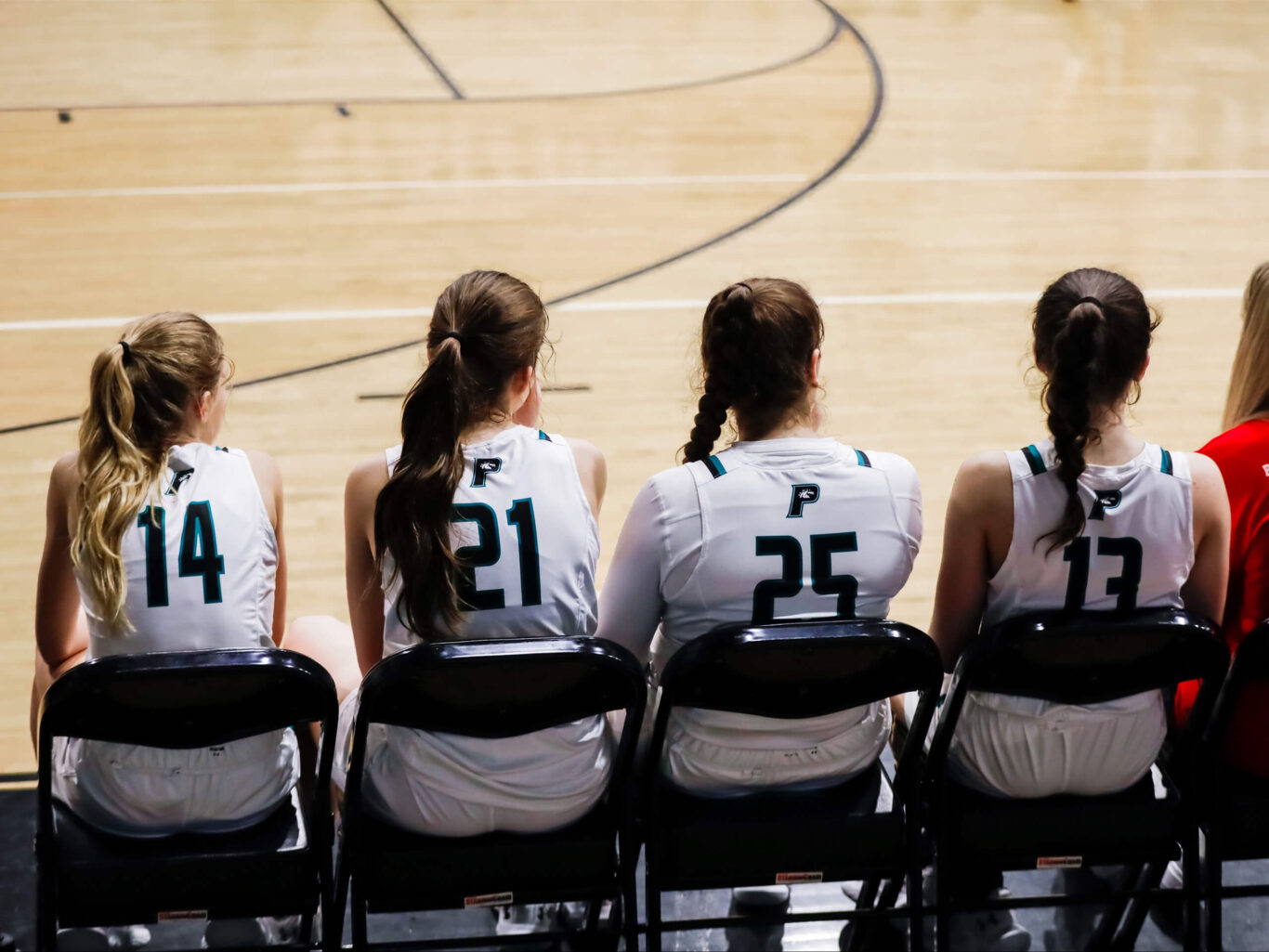 A team of girls' basketball players sitting on the bench.