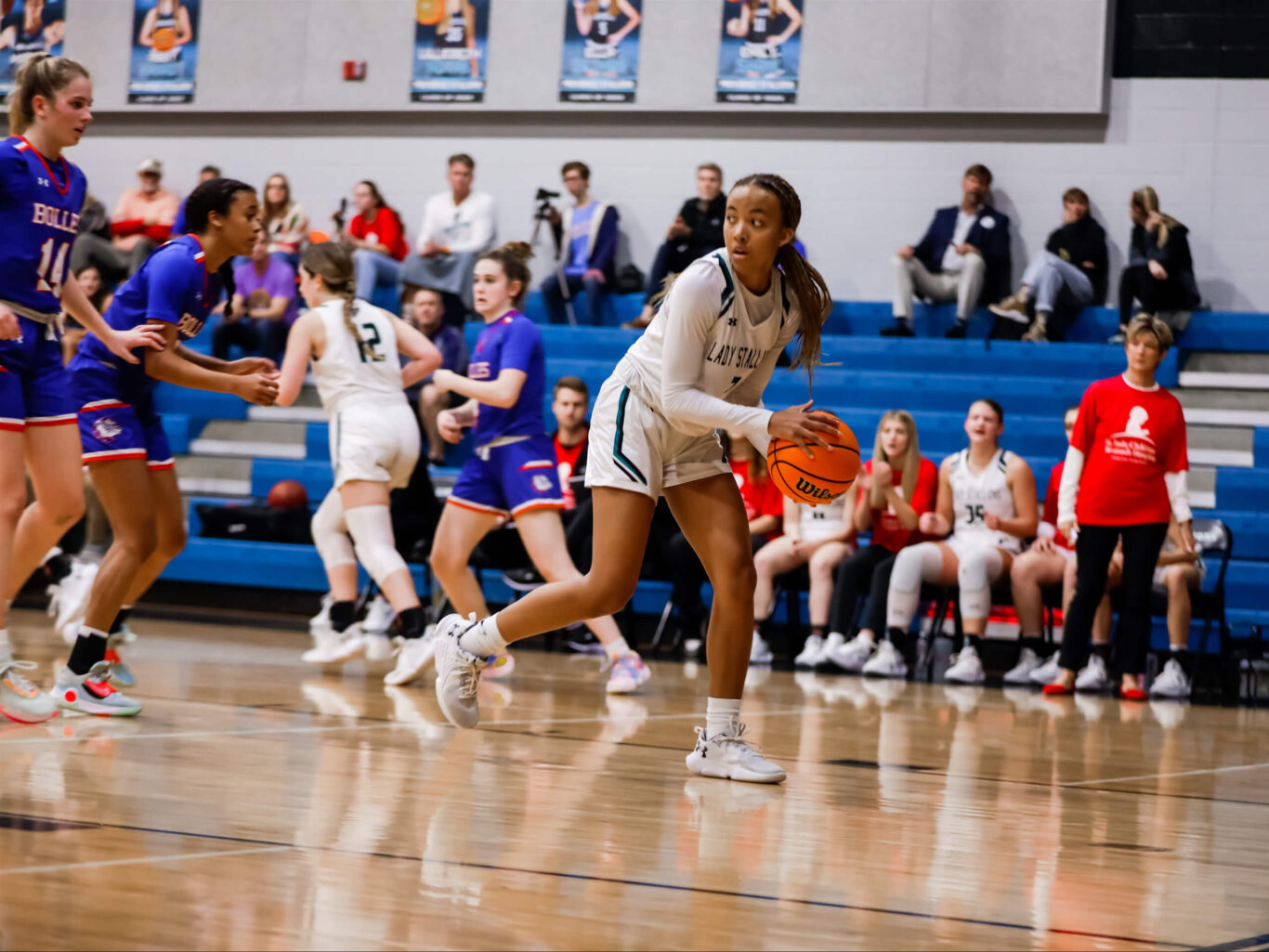 A girls' basketball player dribbling the ball on a court.