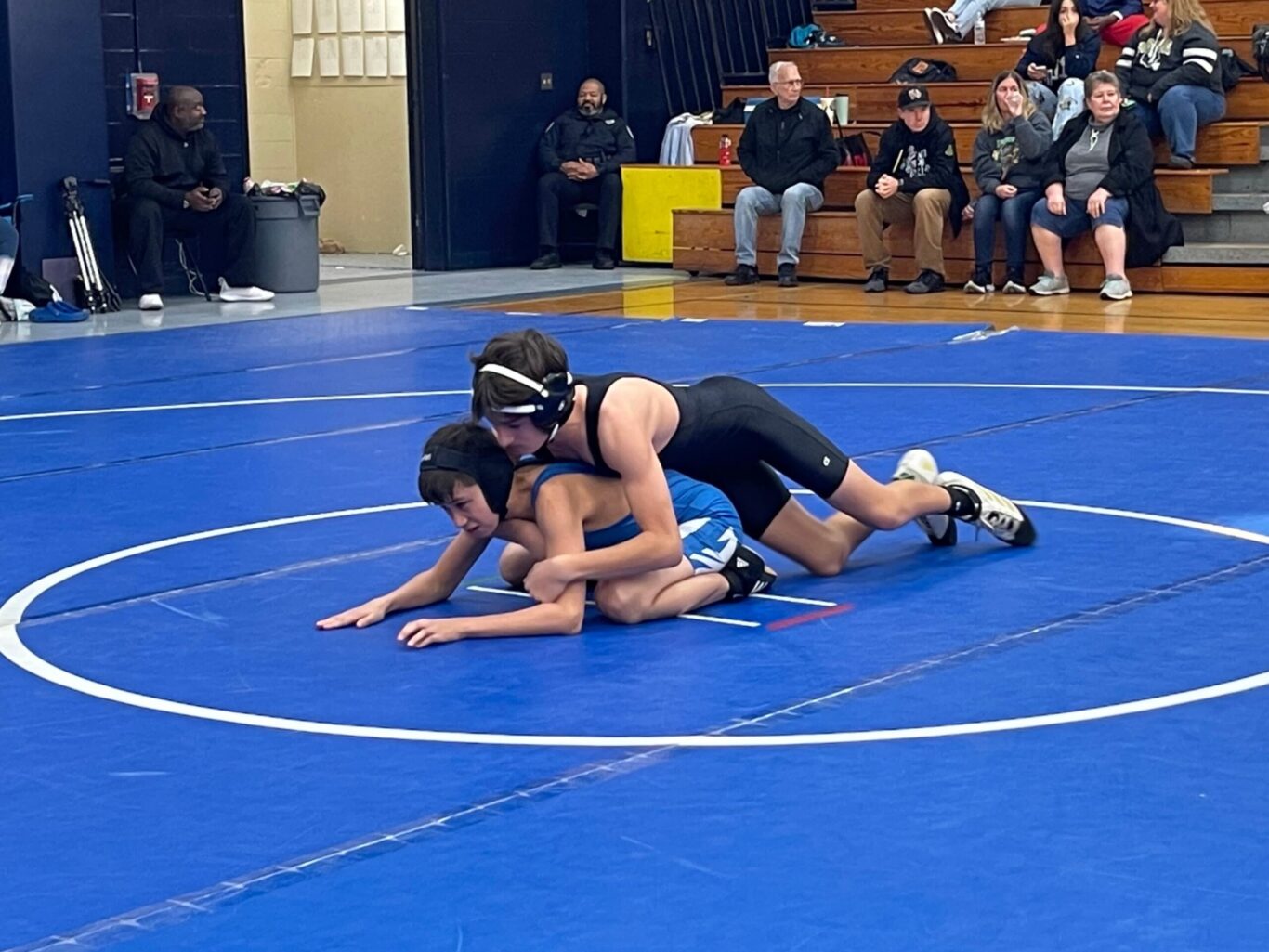 Two wrestlers wrestling on a blue mat.