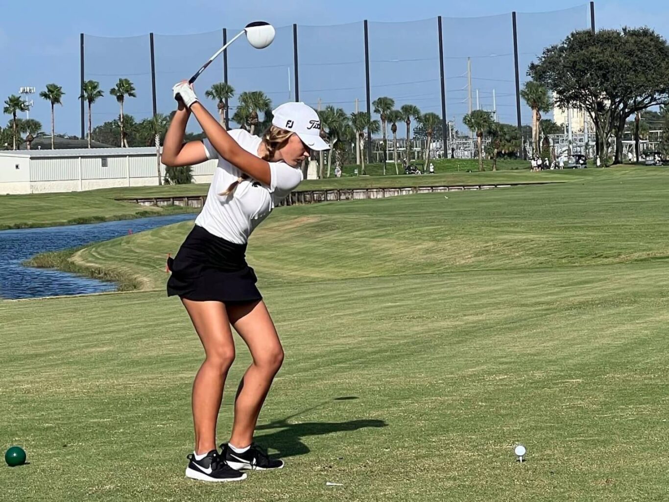 A female golfer hitting a ball on a golf course.