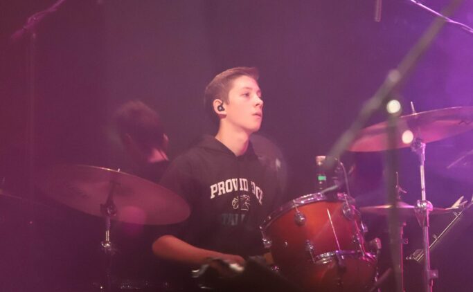 A young man, Demi Tebow, playing drums on the special chapel stage.