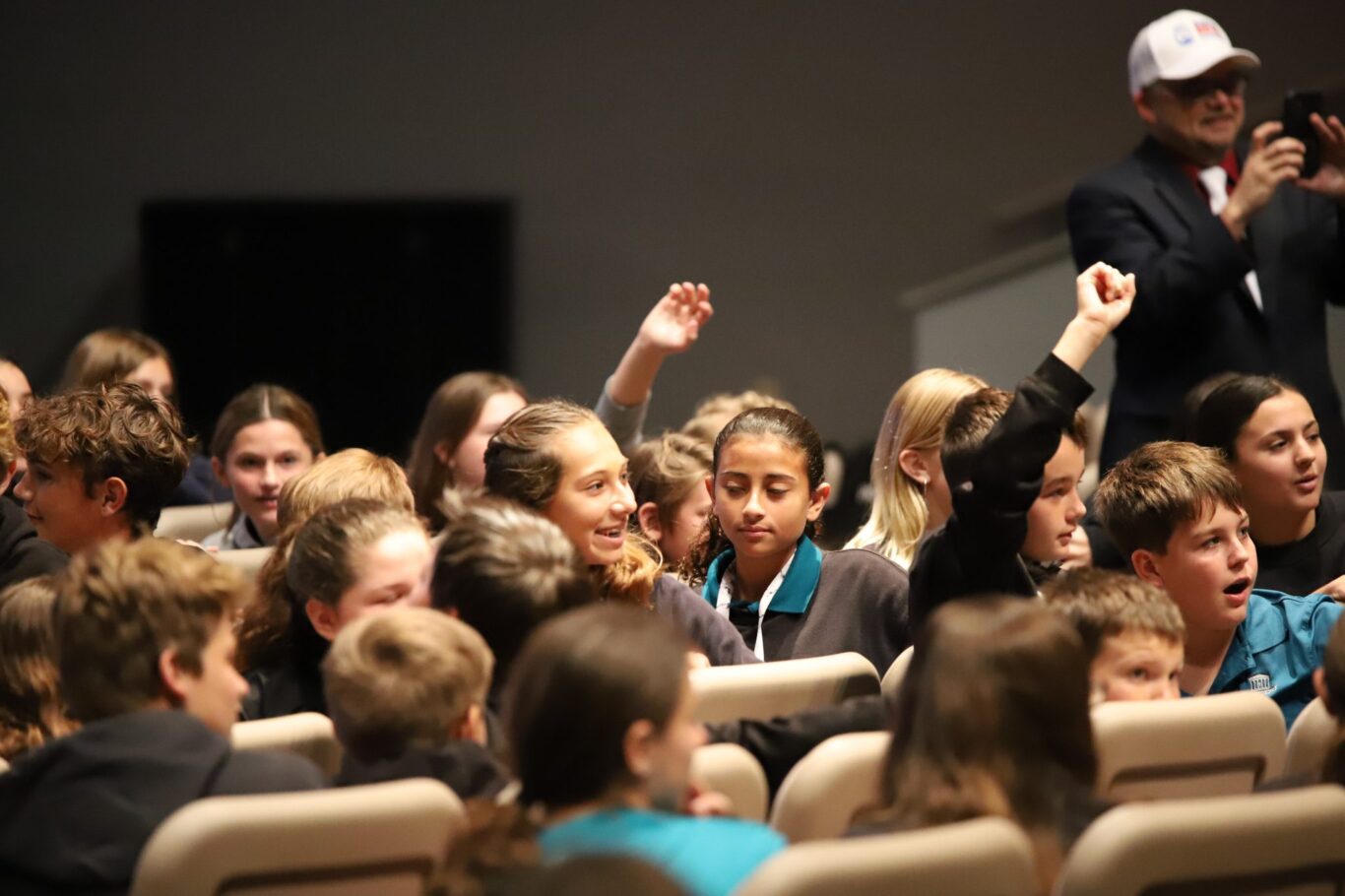 A group of children are sitting in a room with a teacher, engaged in a civics lesson.