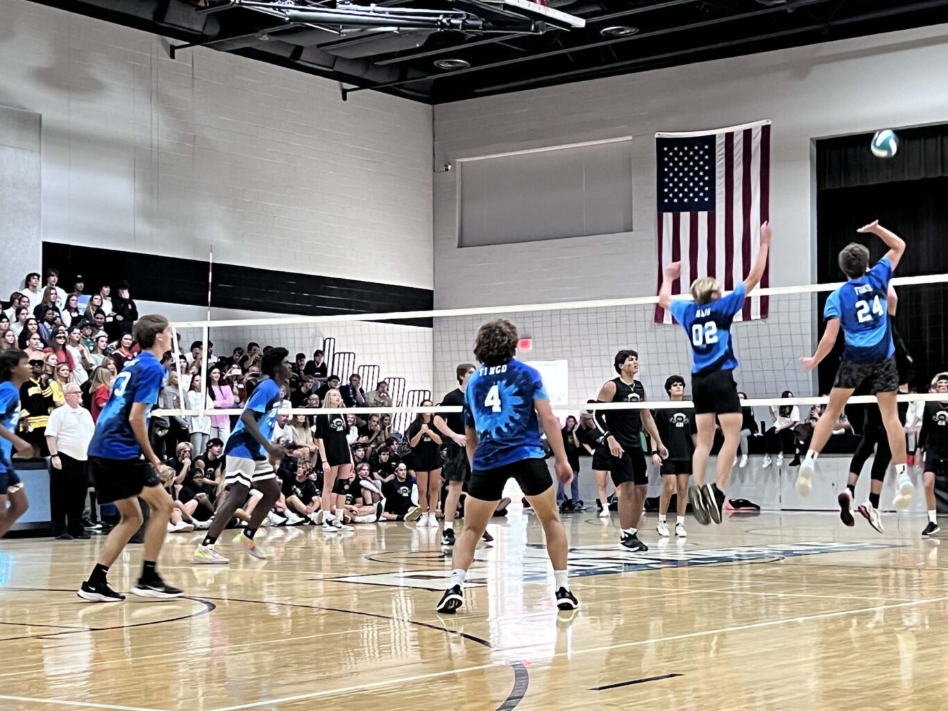 A group of people playing volleyball in a gym during Homecoming.