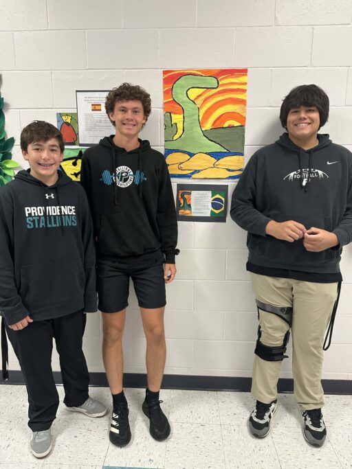 Three Spanish 3 students celebrating in front of a wall of art.