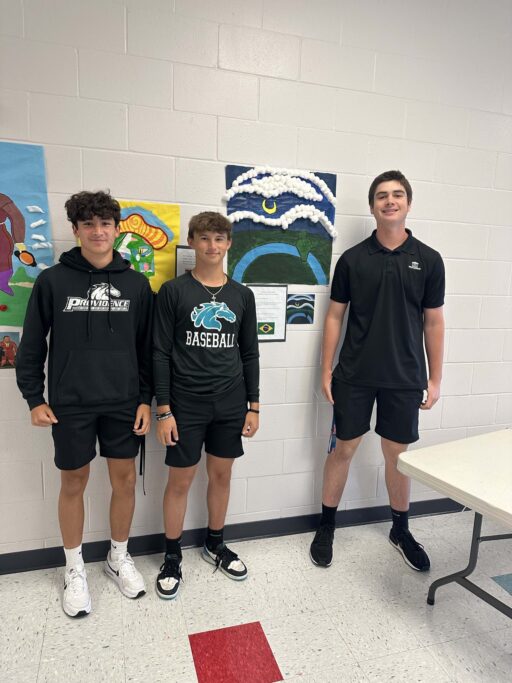 Three young Hispanic students standing next to each other in a room, experiencing Spanish language and immersed in Hispanic culture.