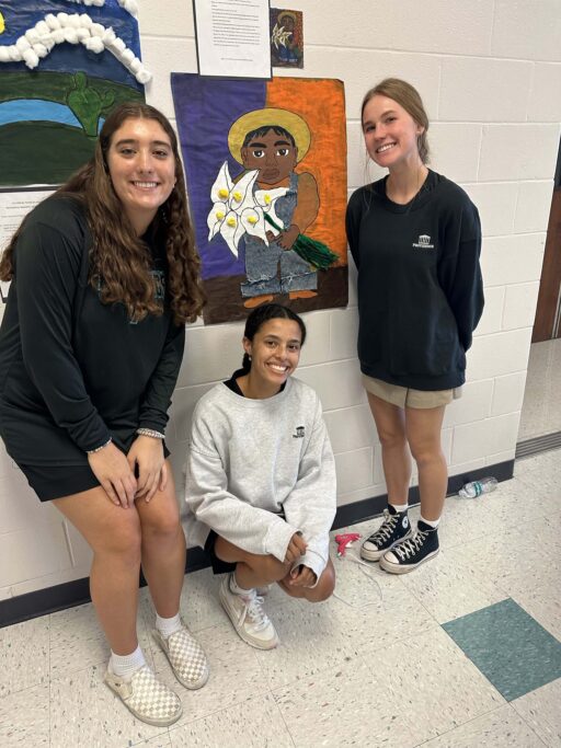 Three Hispanic students posing for a picture in front of a wall.