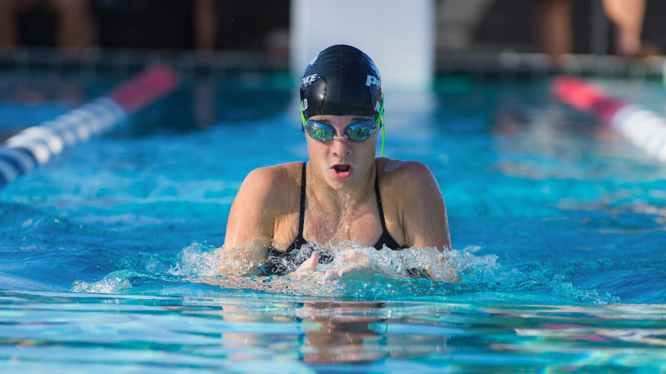 A girl swimming in a pool with goggles on.