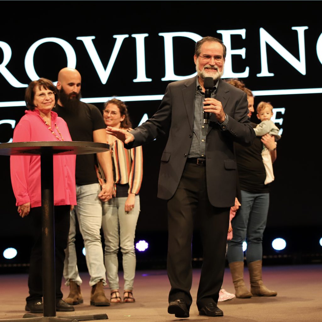 A man engaged in outreach, holding a microphone as he supports Providence Missions.