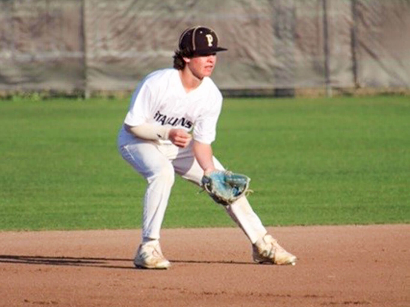 A baseball player is preparing to catch a ball on the field.