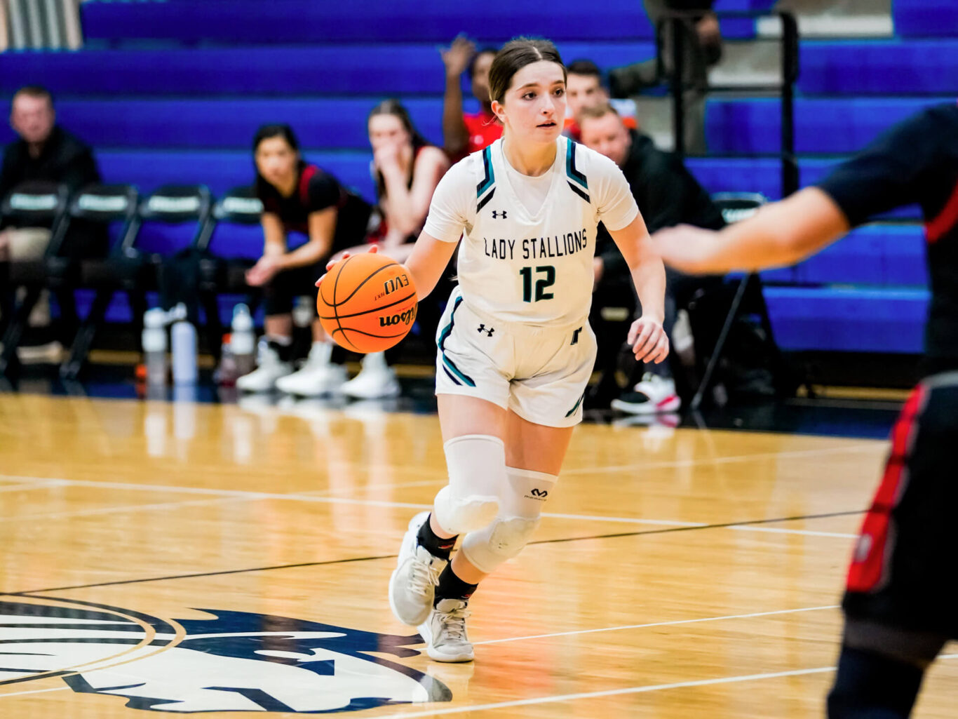 A girls basketball player dribbling the ball on a court.