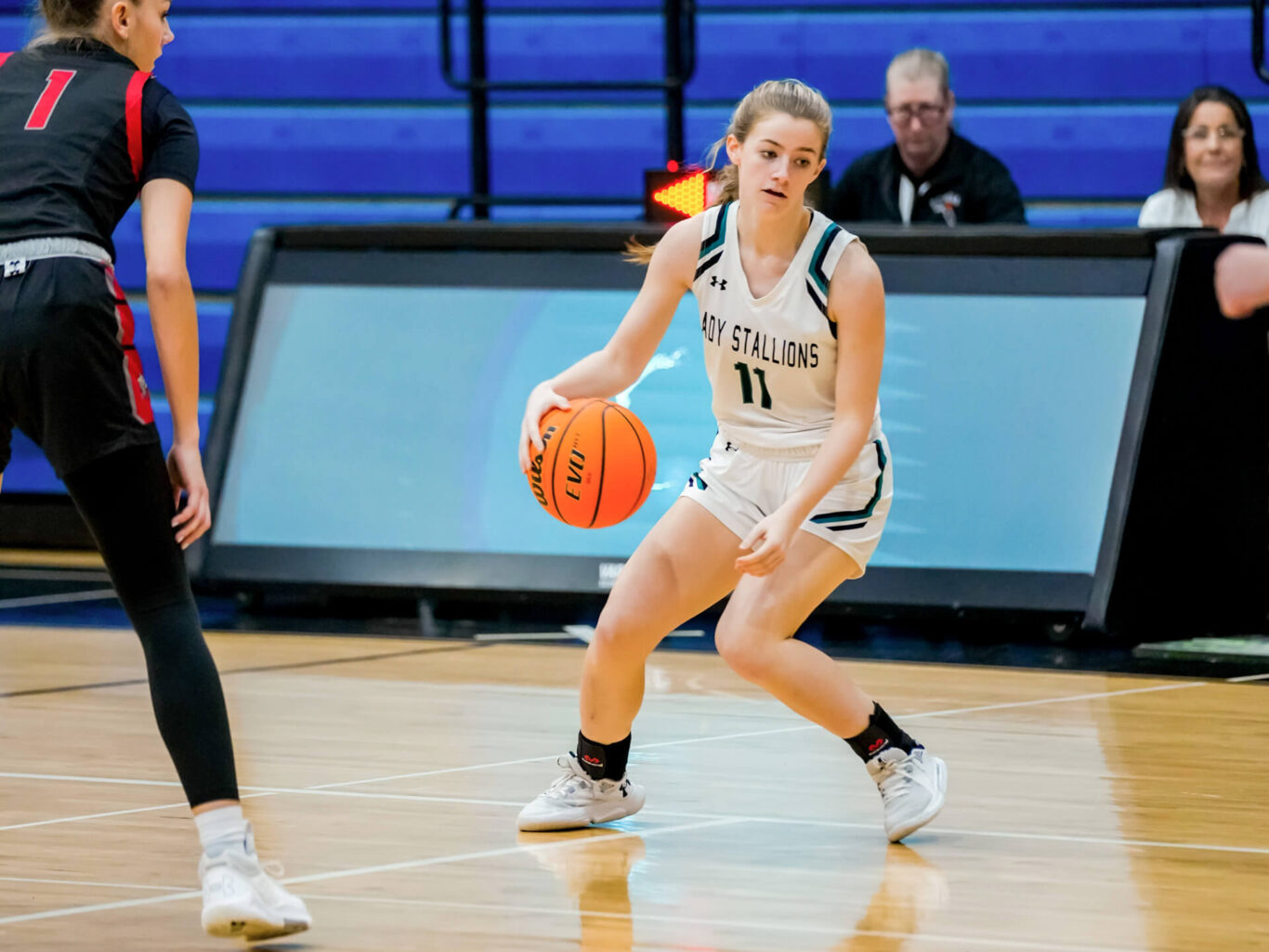 A female basketball player is dribbling the ball on a court while showcasing exceptional skills in girls' basketball.