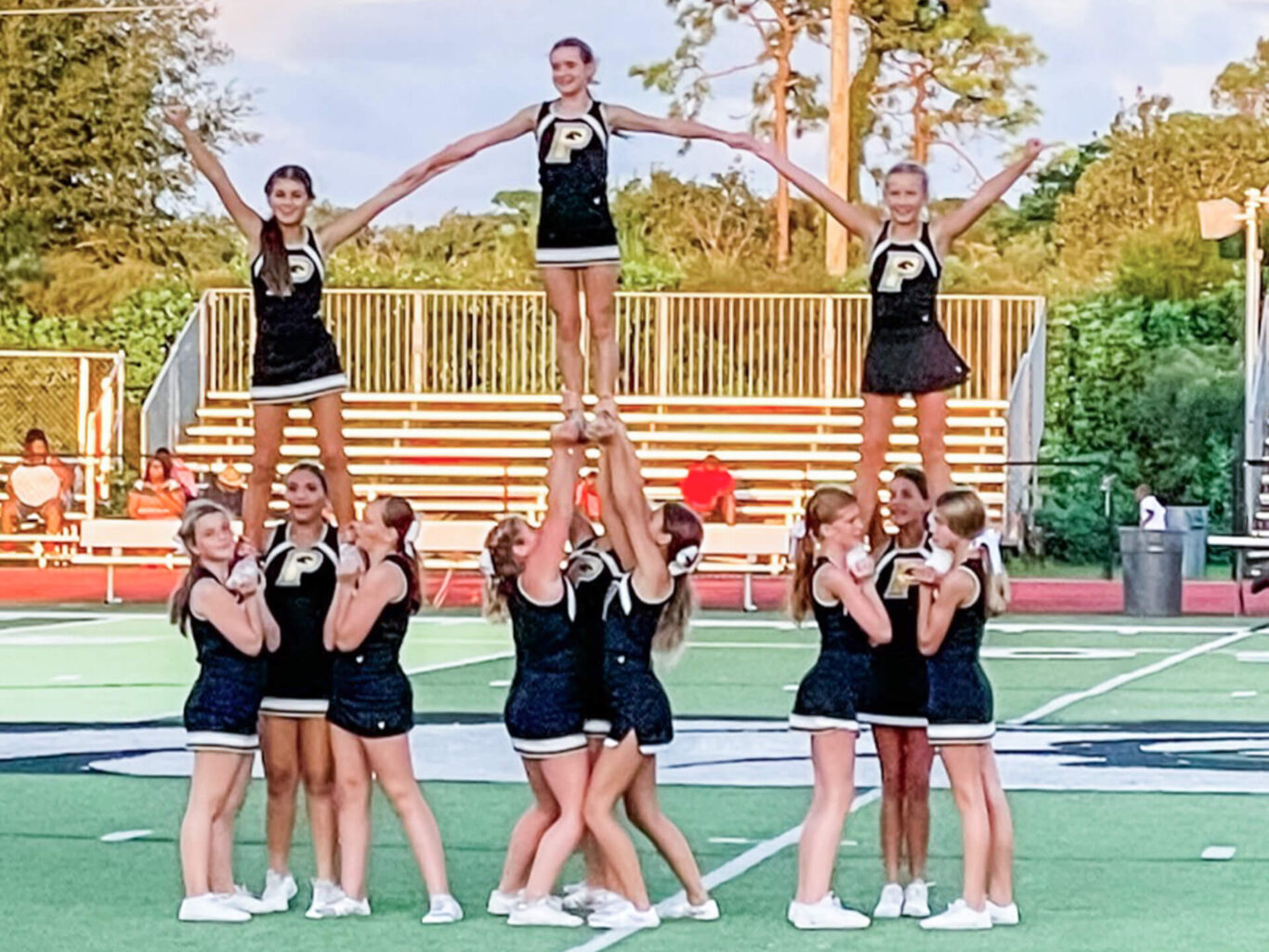 Competitive cheerleaders performing on a football field.