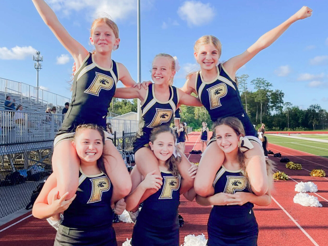 A competitive group of cheerleaders posing on a field.