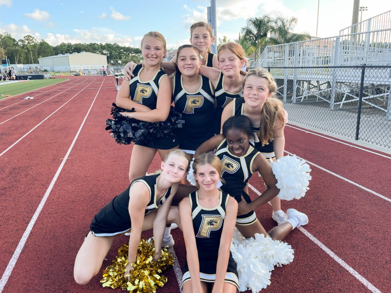 A competitive cheerleading squad posing for a photo on a track.