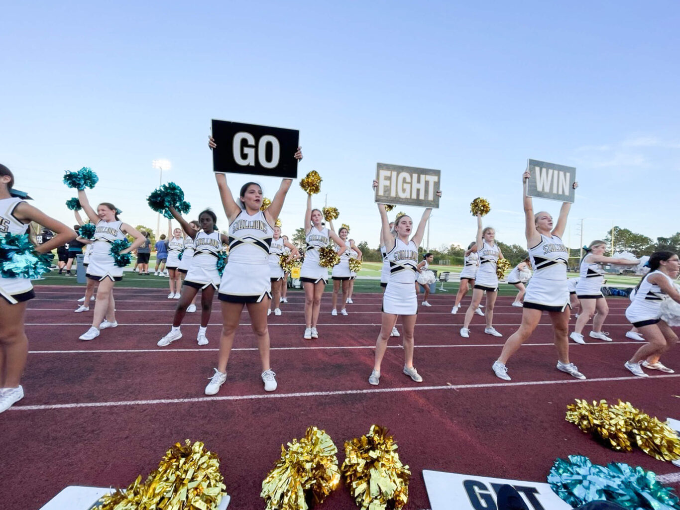 A group of competitive cheerleaders energetically holding signs with the word go.