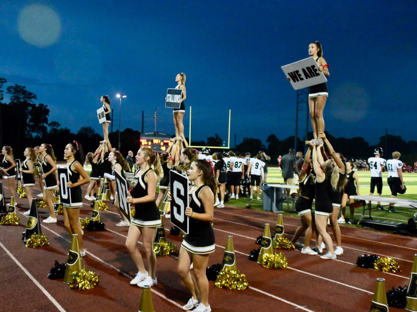 Competitive cheerleaders perform on a football field.