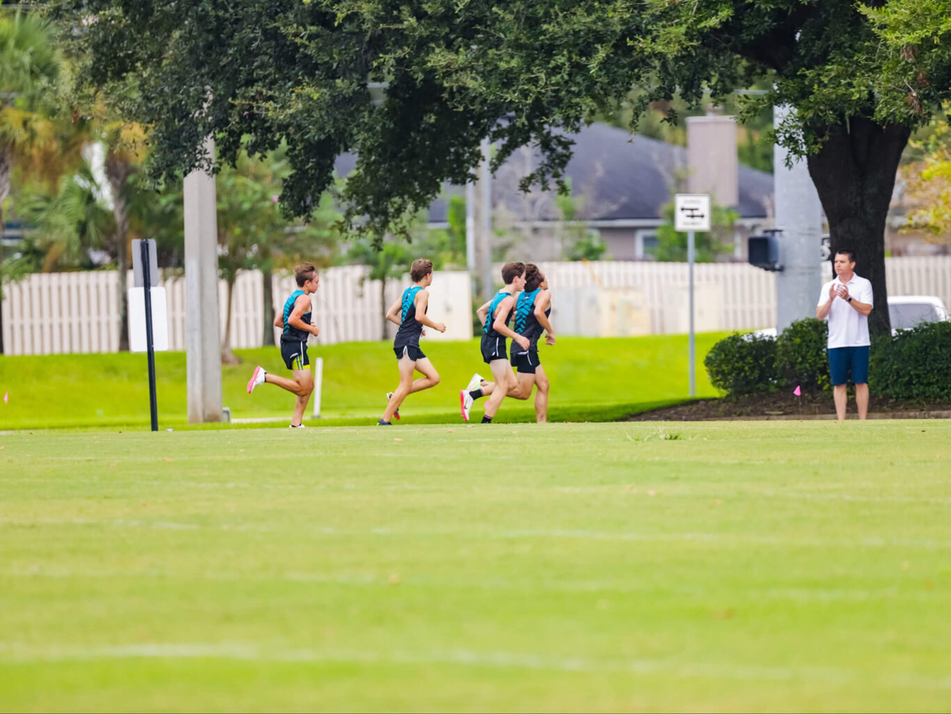 A group of boys running cross country on a grassy field.