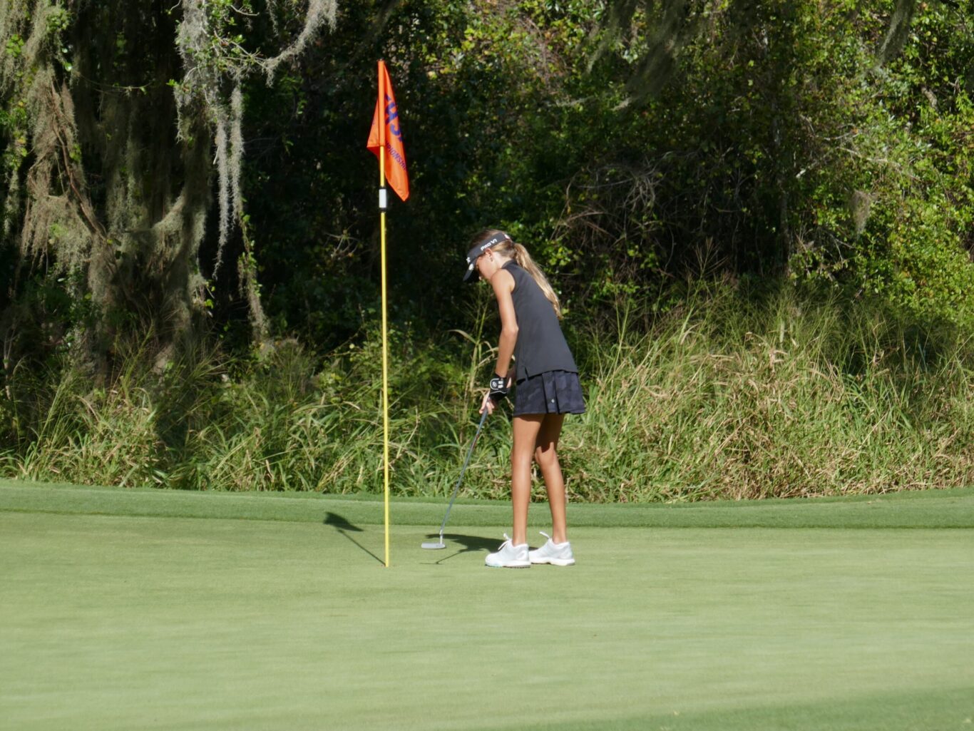 A woman is putting a golf ball on a green.