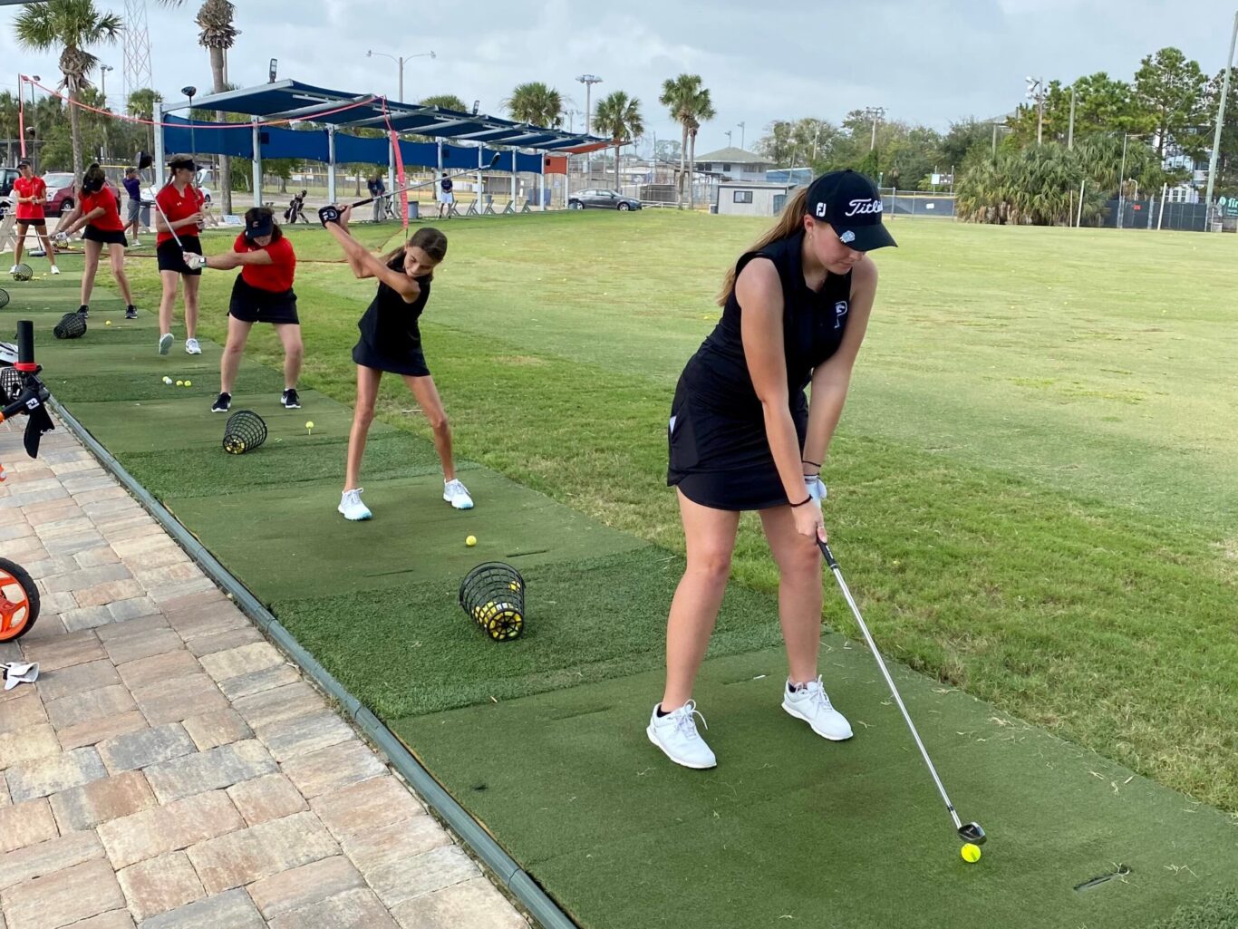 A group of girls practicing golf on a green.