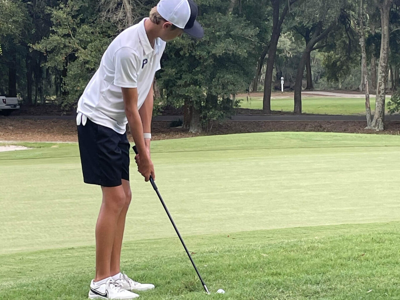 A young man is skillfully placing a golf ball on a pristine green.