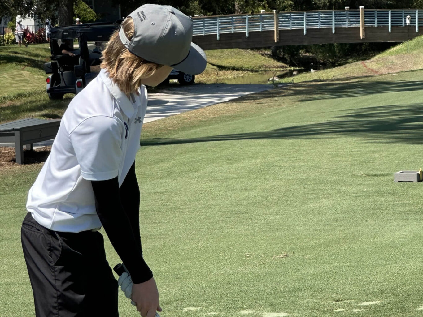A Golf Boy is hitting a golf ball on a golf course.