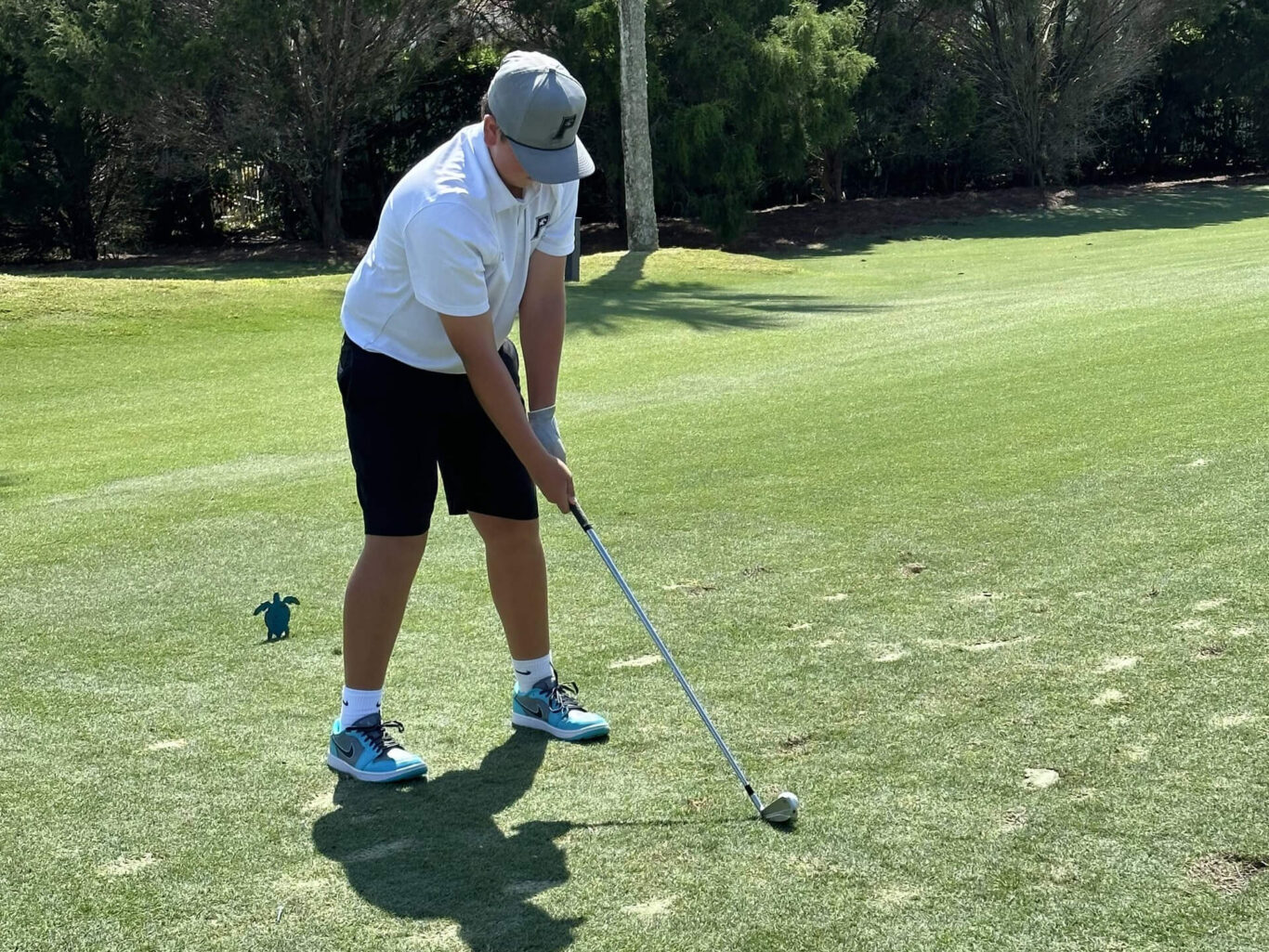 A Golf Boy hitting a golf ball on a golf course.