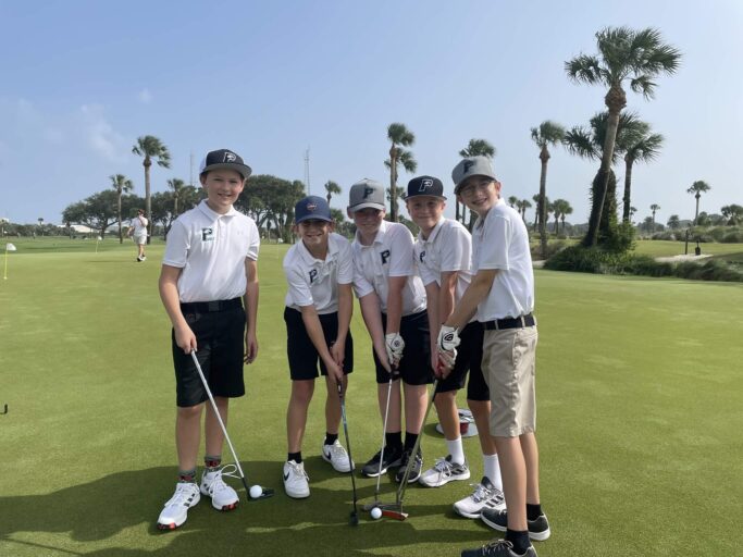 A group of boys posing for a picture on a golf course.
