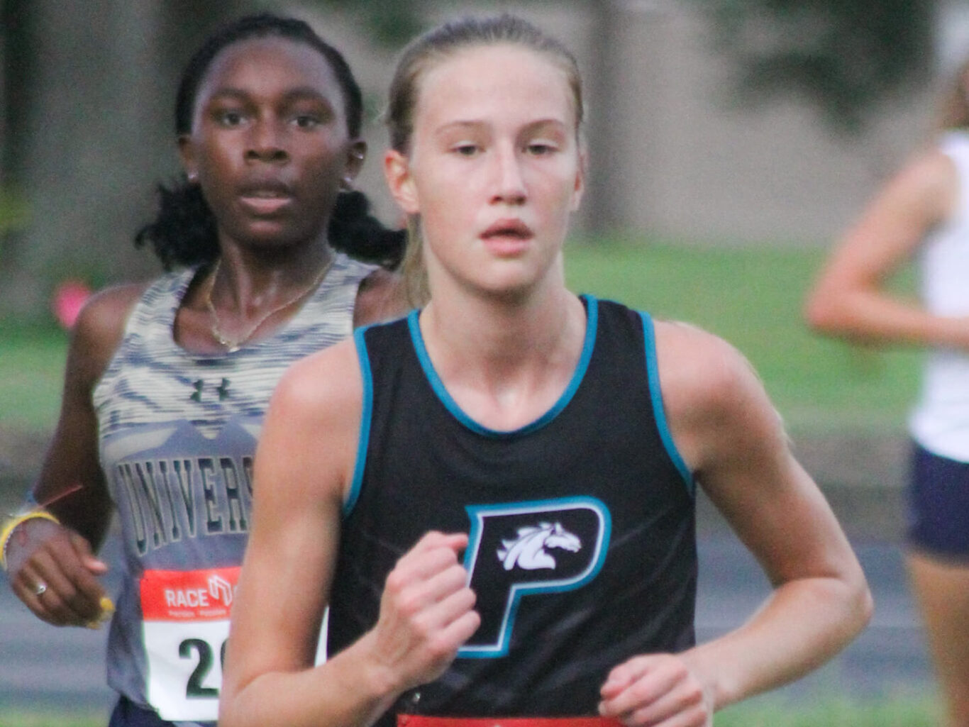 Two girls participating in a cross country race.