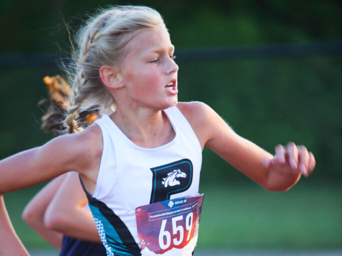 A cross country girl running in a race.
