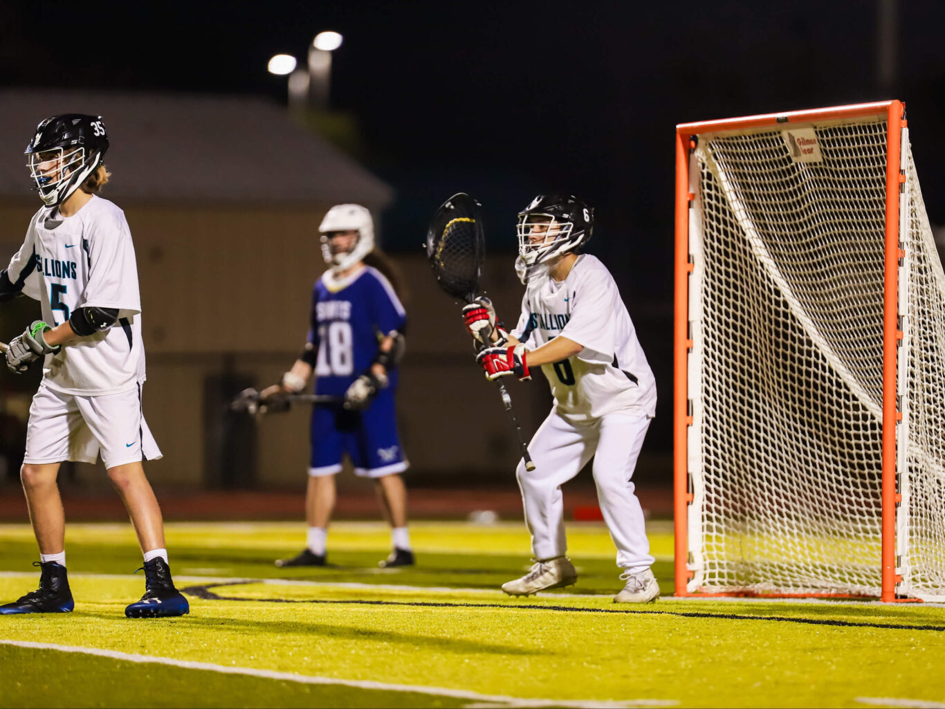 A group of boys playing lacrosse on a field.