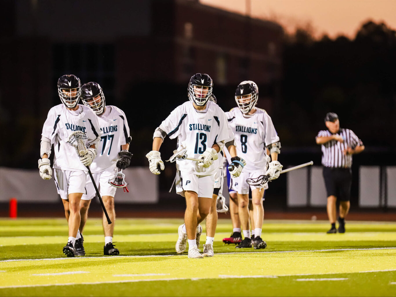 A group of lacrosse boys walking on a field.