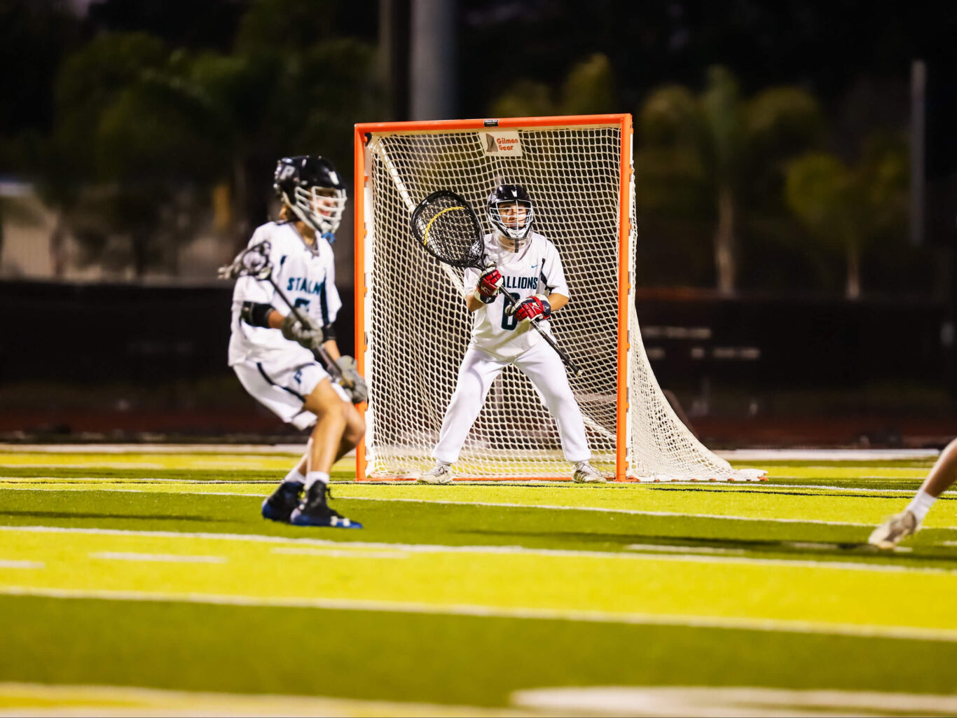A boys lacrosse player in action on a field.