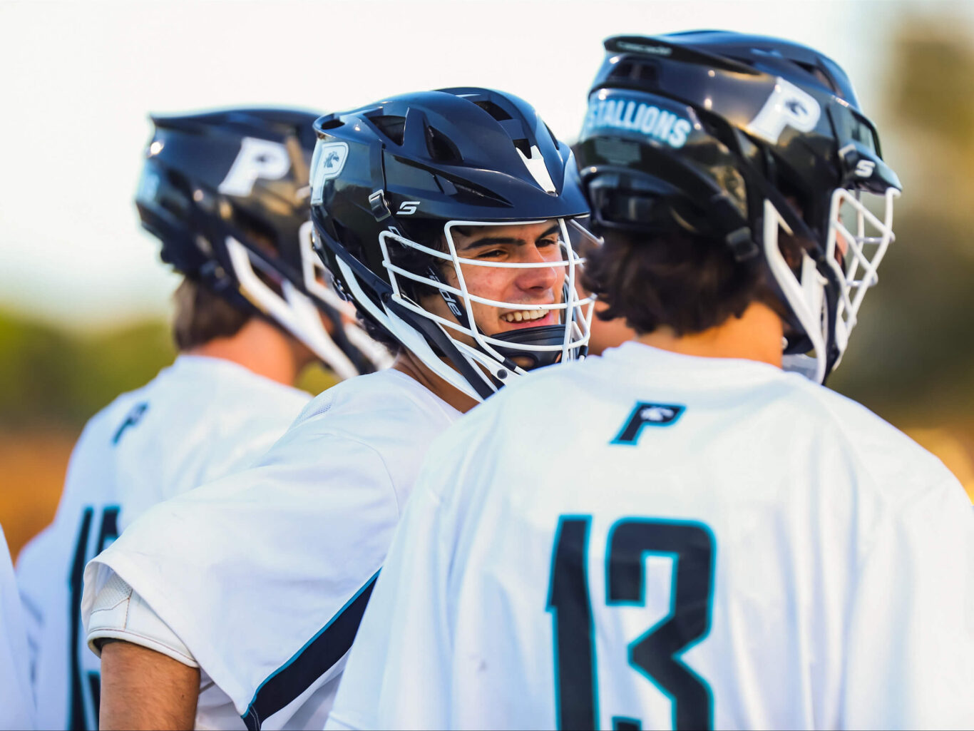 A group of lacrosse boys are talking to each other.