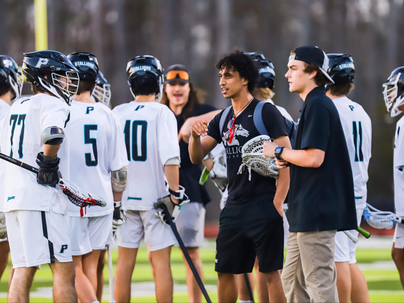 A group of lacrosse boys huddle together on the field.