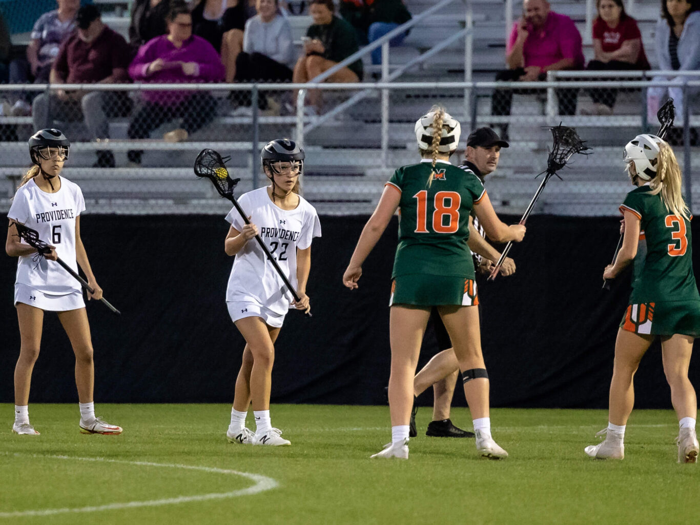 A team of girls playing lacrosse on a field.