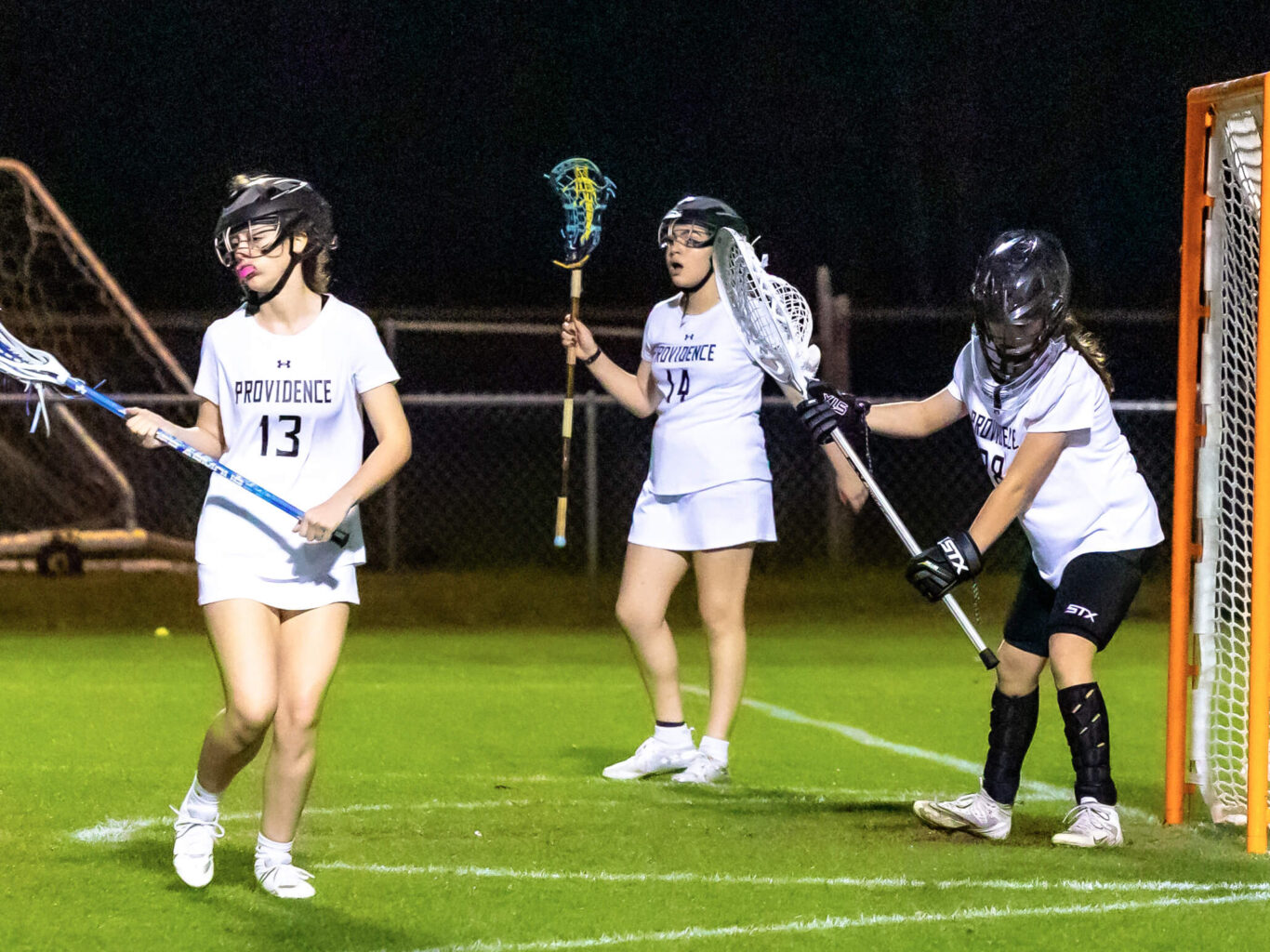 A group of girls engaged in a lacrosse game on a field.