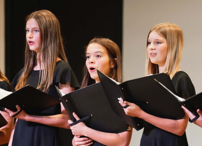 An ensemble of girls harmonizing in a choir, showcasing their talent in the performing arts.