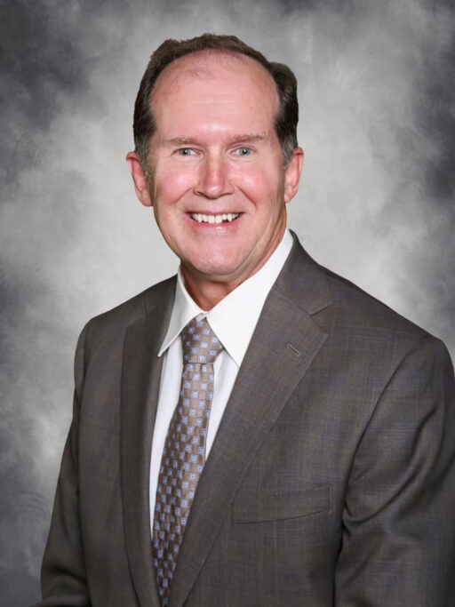 Rick Jones in a suit and tie smiles for the camera.