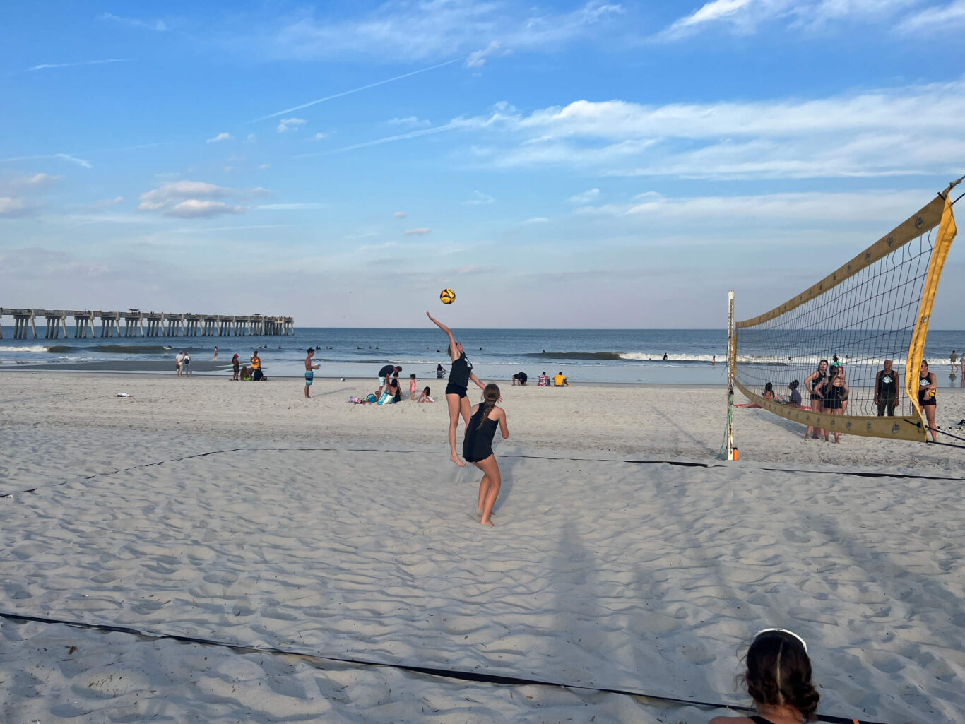 A group of girls playing beach volleyball.