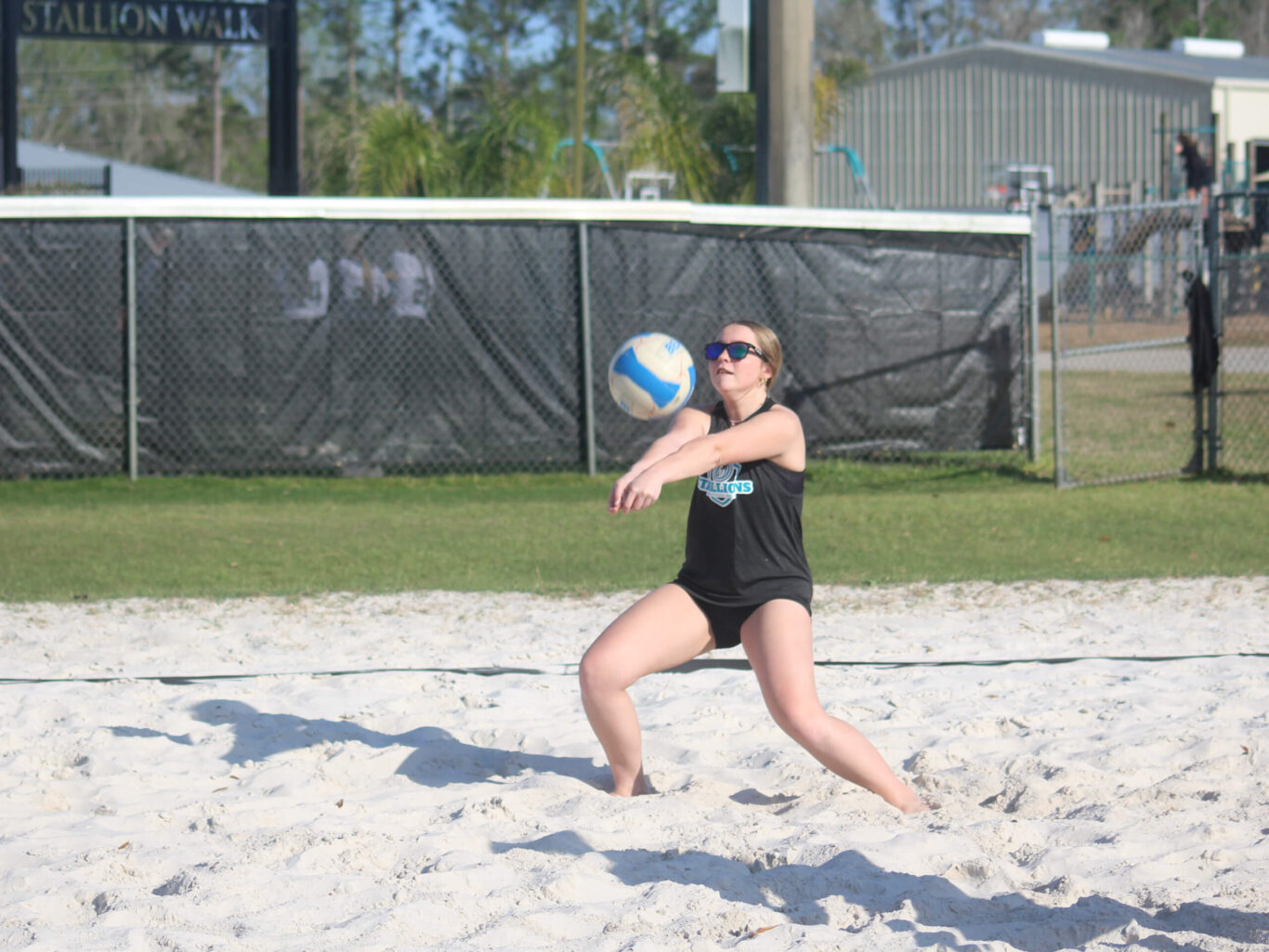 A girl is playing volleyball on a beach.