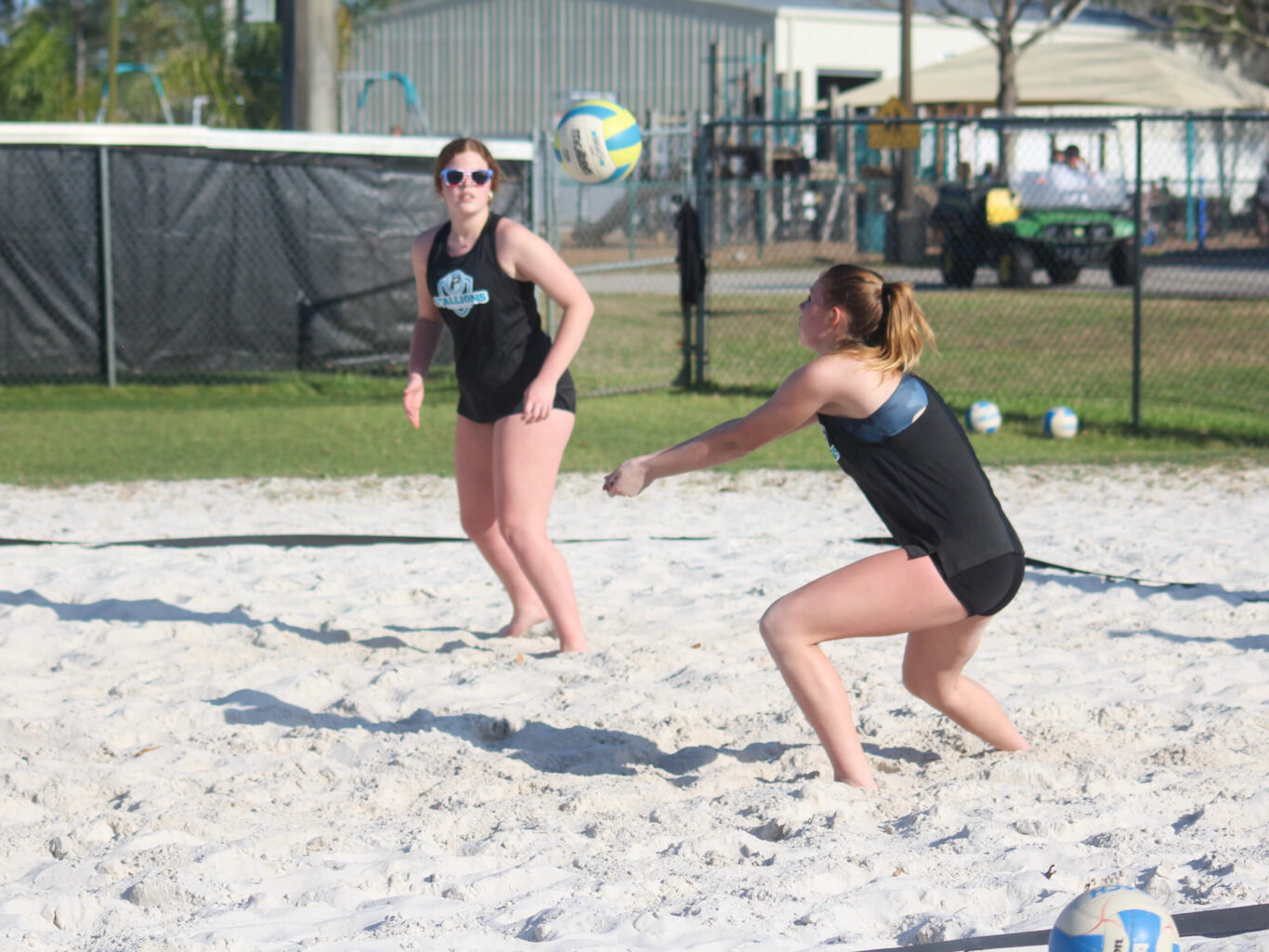 Two girls playing a game of beach volleyball.