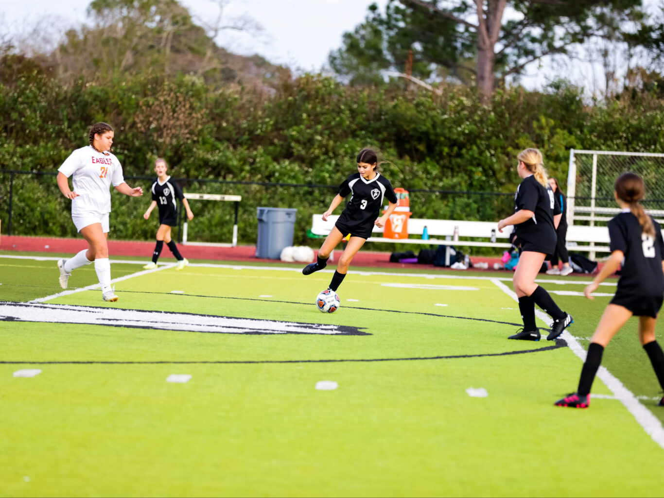 A group of girls engaging in soccer on a green field.