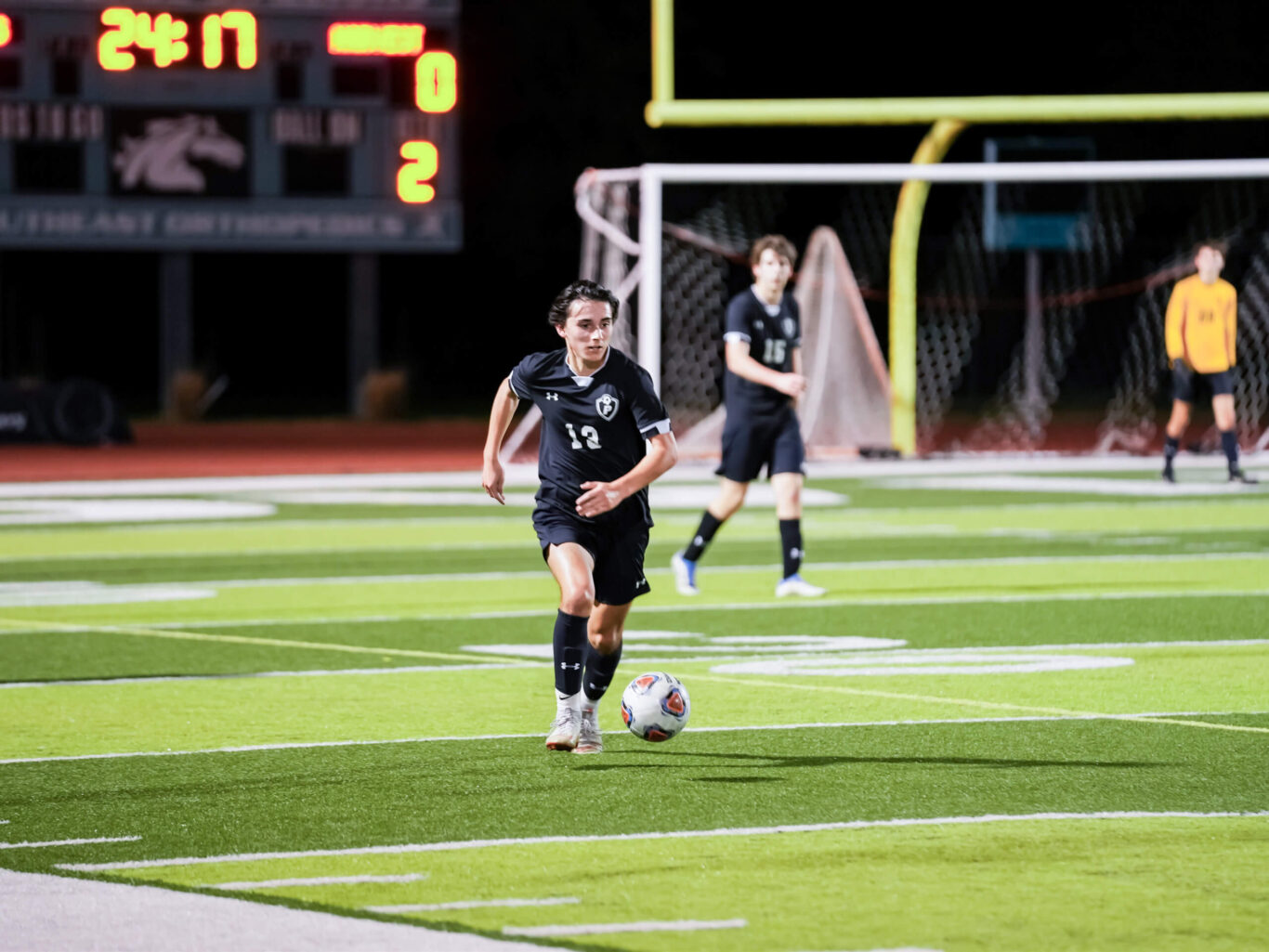 A young soccer player is sprinting across the field during an intense night game.