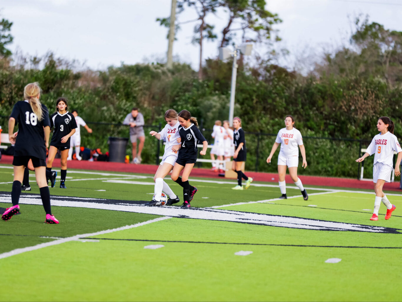 A group of girls engaged in a spirited game of soccer on a field.