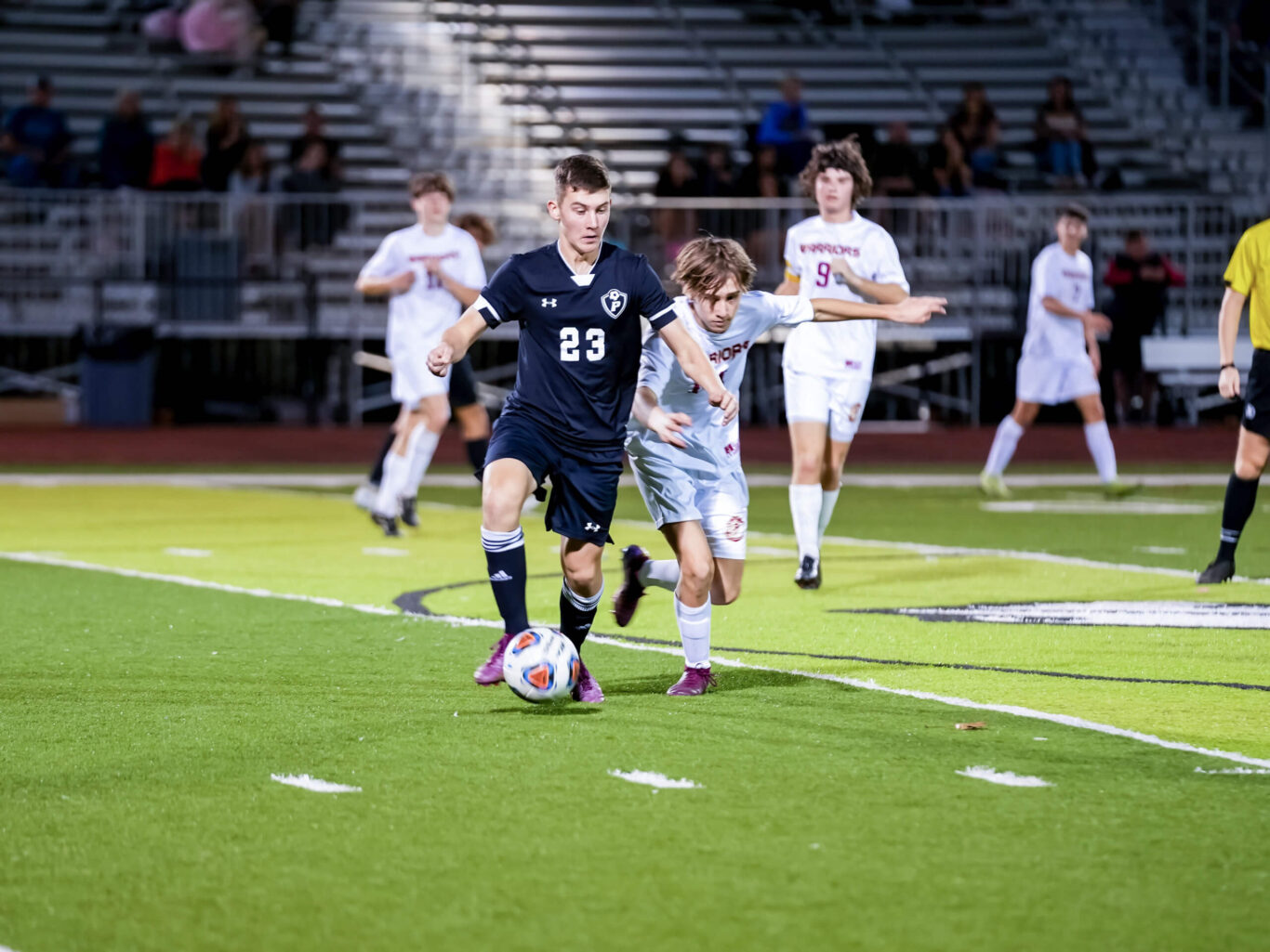 Two soccer boys running for the ball on a soccer field.