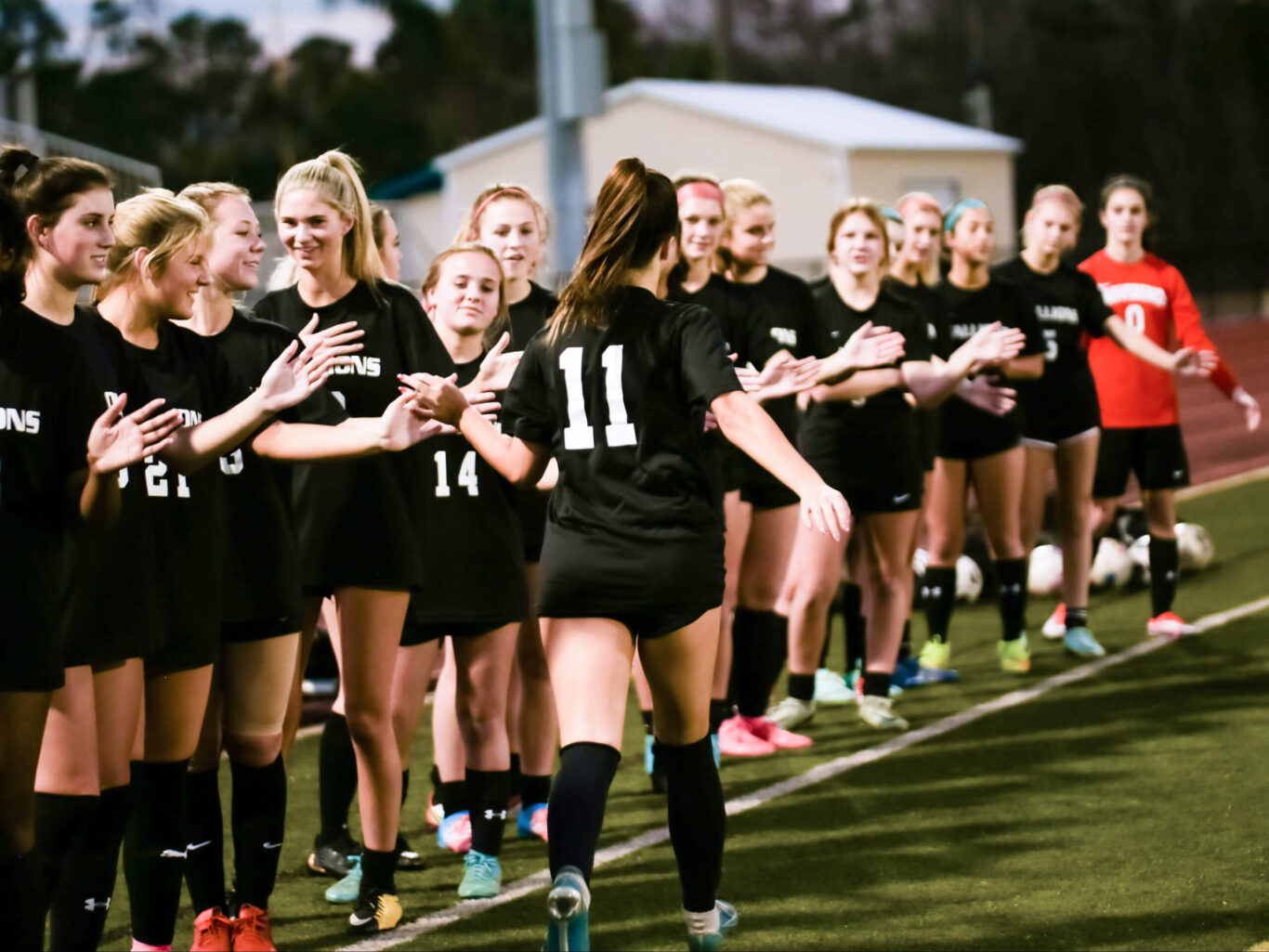 A group of girls playing soccer on a field.