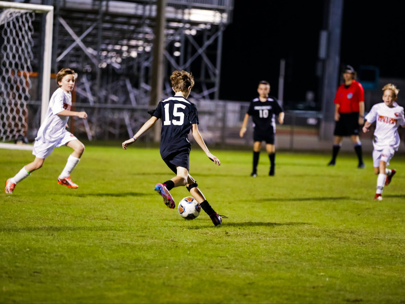 A group of boys playing soccer at night.